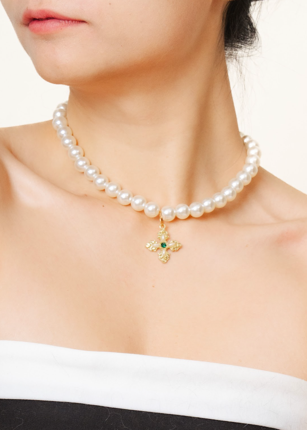 A woman wearing a faux pearl necklace with a customizable charm pendant.