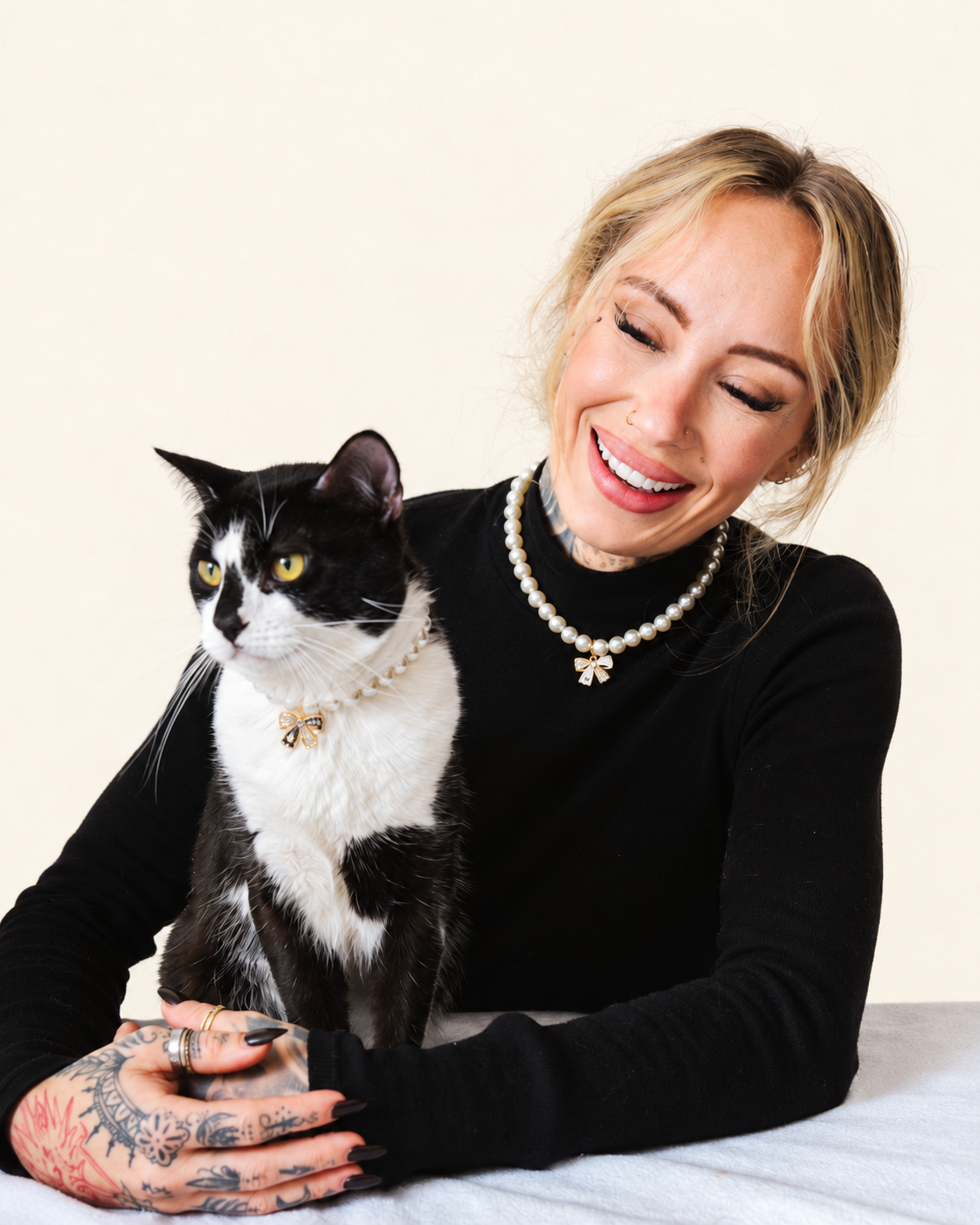 Woman and her tuxedo cat wearing matching faux pearl necklaces with bow charms