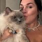 Woman and her fluffy Ragdoll cat wearing matching pearl necklaces with colorful charms