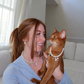 Woman holding her Abyssinian cat, both wearing matching faux pearl necklaces