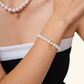 Close-up of a woman wearing a freshwater pearl bracelet and matching necklace with letter charms