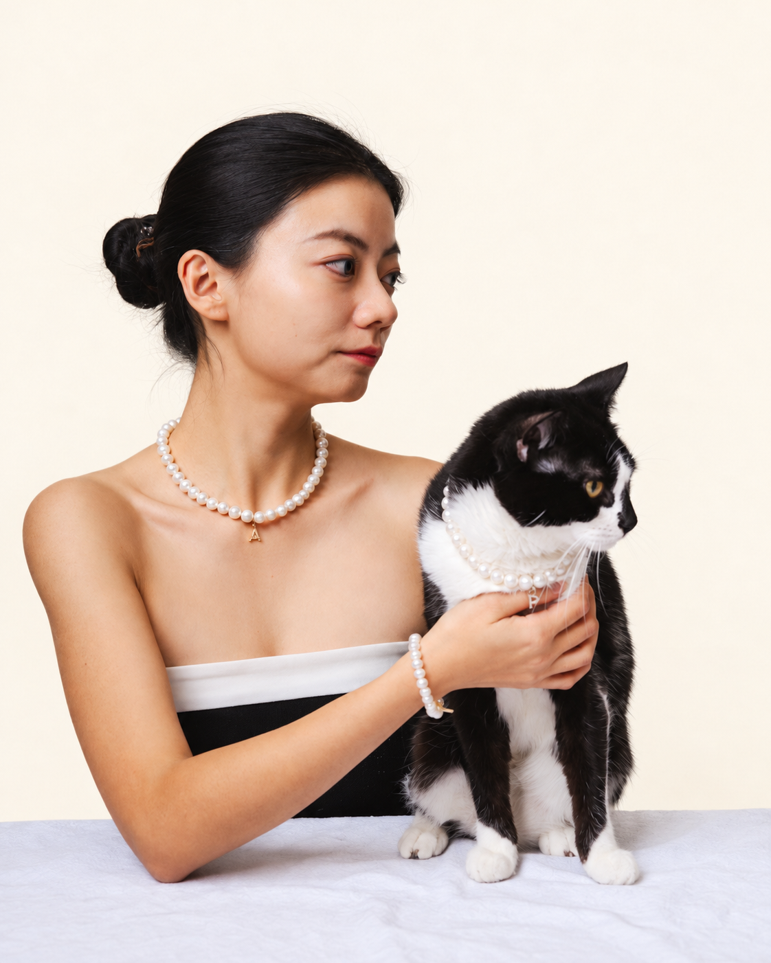 Woman and her tuxedo cat wearing matching freshwater pearls