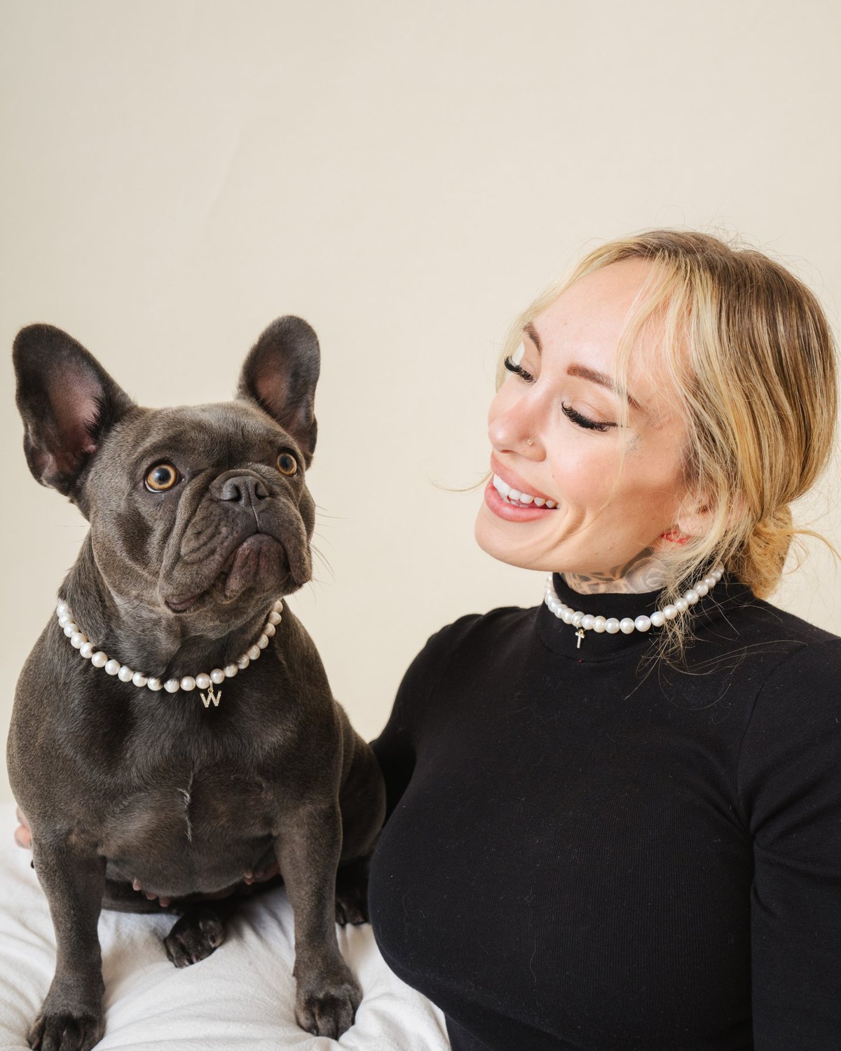 Woman and her French bulldog wearing matching freshwater pearl necklaces with letter charms