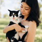 Woman outdoors holding her tuxedo cat, both in matching freshwater pearl necklaces