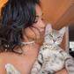 Woman holding her tabby cat, both wearing matching freshwater pearl necklaces with charms